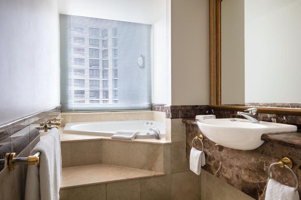 a bathroom with a tub and a sink and a mirror at Mantra Legends Hotel in Gold Coast