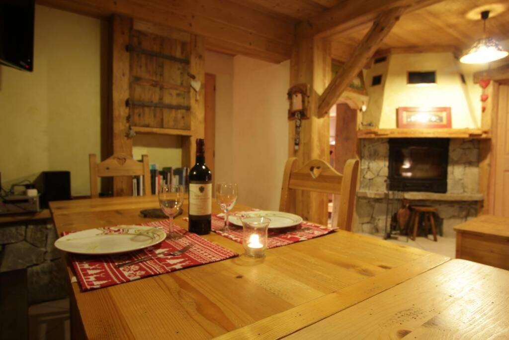 una mesa de madera con una botella de vino y copas en appartement cozy dans chalet 6 pers voiture 4 roues motrice a dispo, en La Clusaz