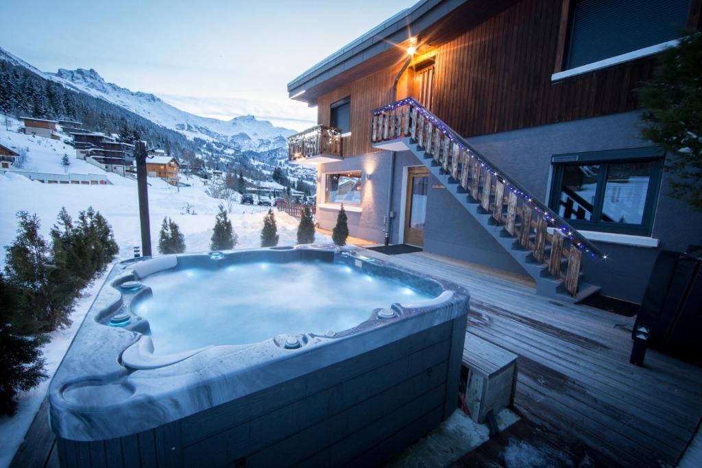 a hot tub on a deck next to a house at Hôtel Spa L'Oxygène in Valmorel