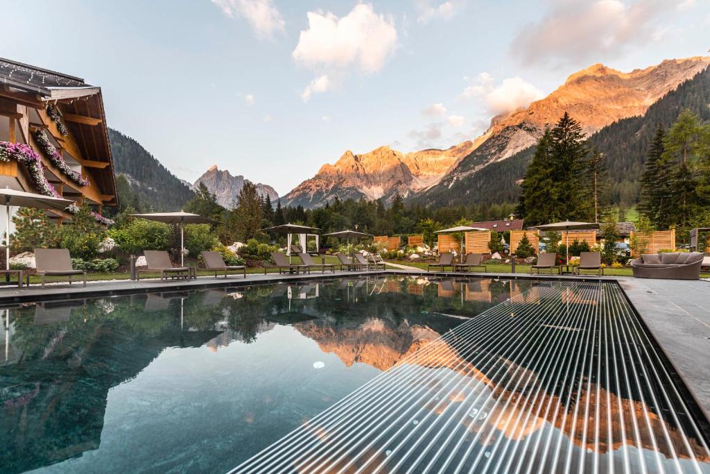 una piscina dell'hotel con montagne sullo sfondo di BAD MOOS - Aqua Spa Resort a Sesto