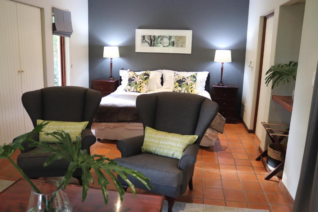 um quarto com 2 cadeiras, uma cama e uma mesa em Heuglins Lodge em White River