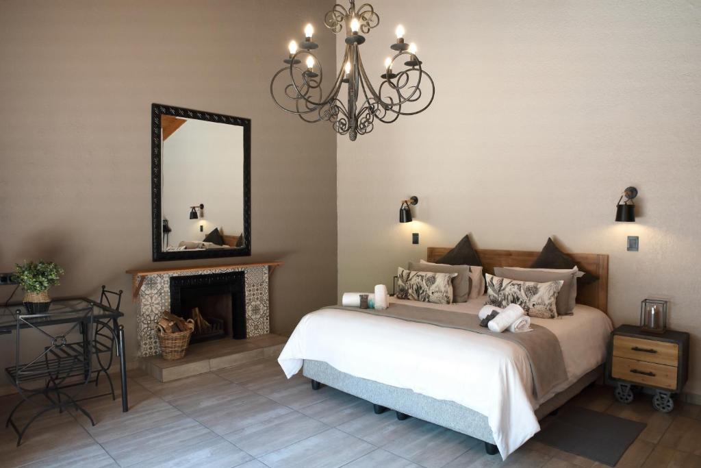 a bedroom with a bed and a mirror and a fireplace at Greenfields Guesthouse & Restaurant in Alberton