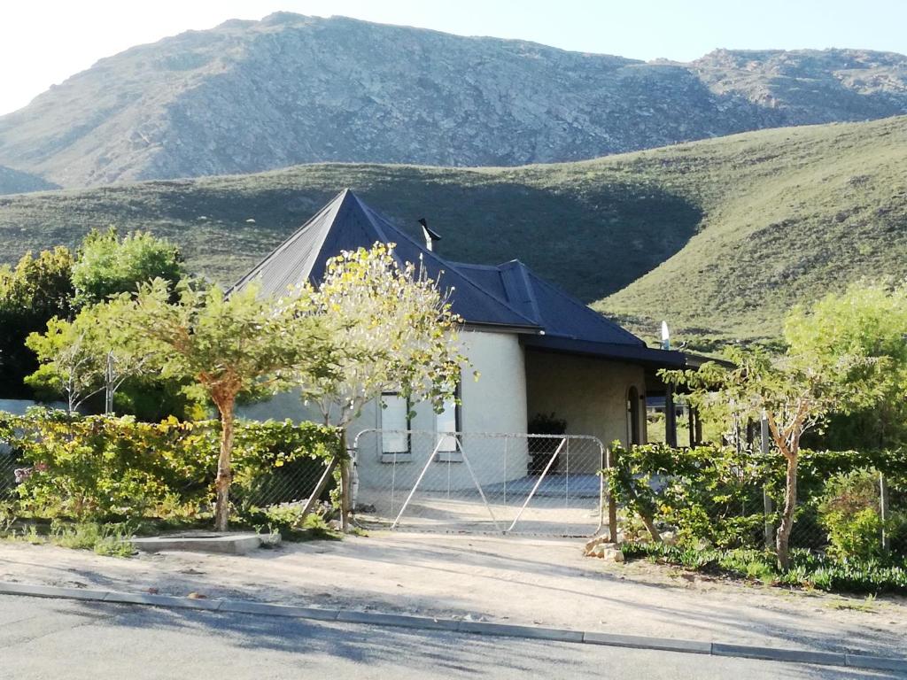 uma casa com um telhado preto com montanhas ao fundo em Montagu Ronda-View em Montagu