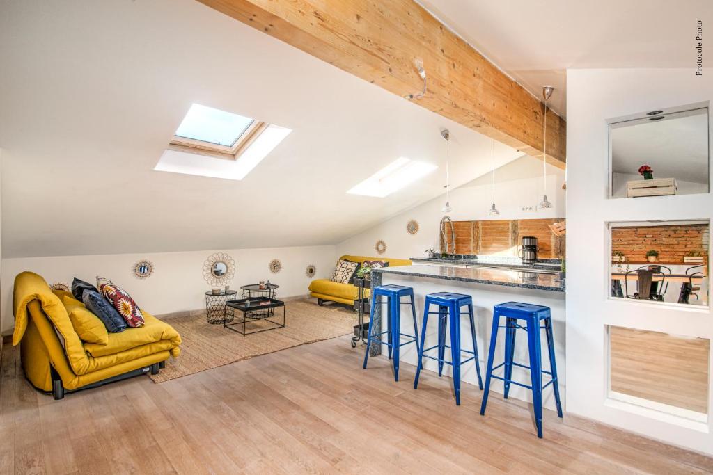 a kitchen and living room with a yellow couch and stools at NOCNOC - Le Mosaïque, centre Toulouse in Toulouse