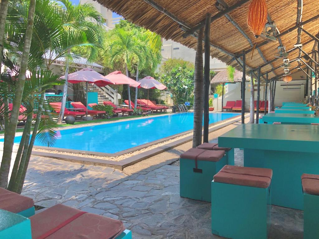 a pool with tables and chairs and palm trees at Mui Ne Hills Budget Hotel in Mui Ne
