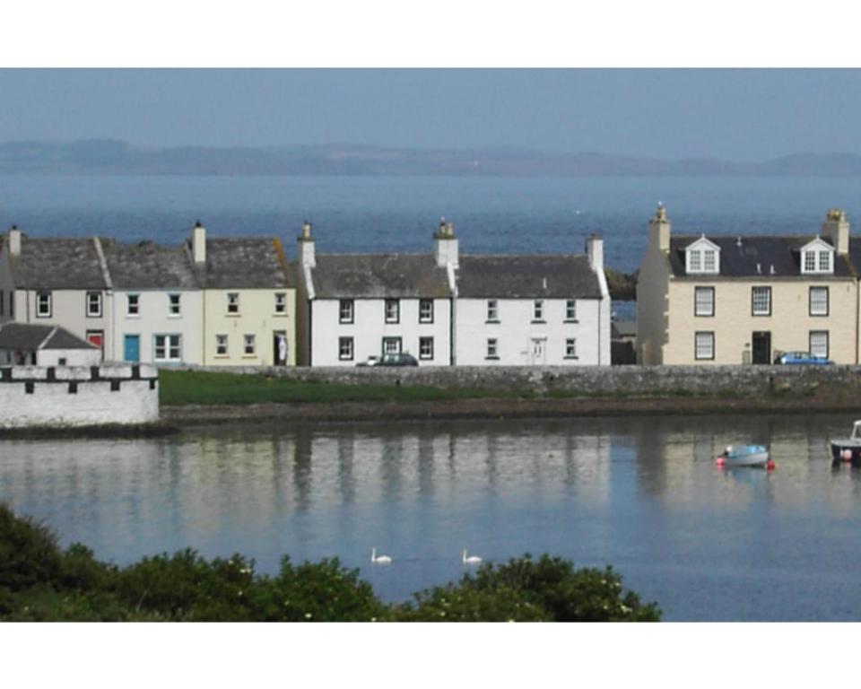 a group of white buildings next to a body of water at Colebrook Cottage in Isle of Whithorn