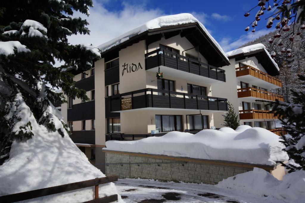 un bâtiment avec de la neige devant lui dans l'établissement Haus Aida, à Saas-Fee