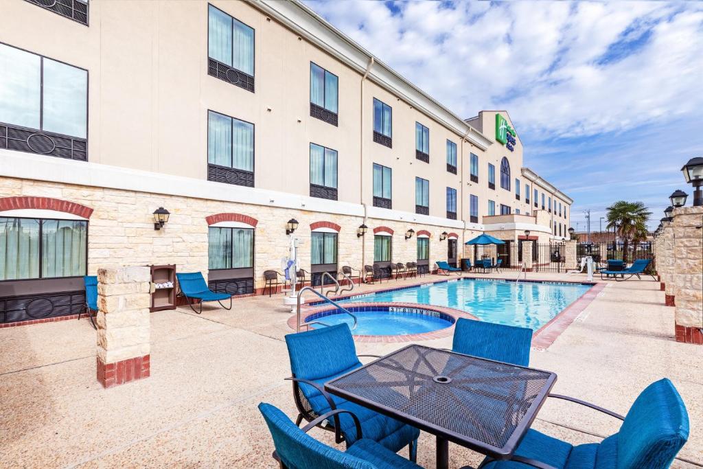 FloresvilleにあるHoliday Inn Express Hotel & Suites Floresville by IHGのホテルのパティオ(テーブル、椅子、プール付)