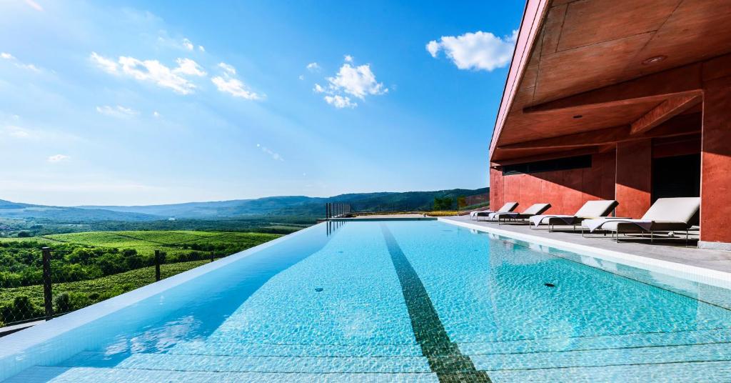 a swimming pool with chairs and a building at Winery & Design hotel ROXANICH in Motovun