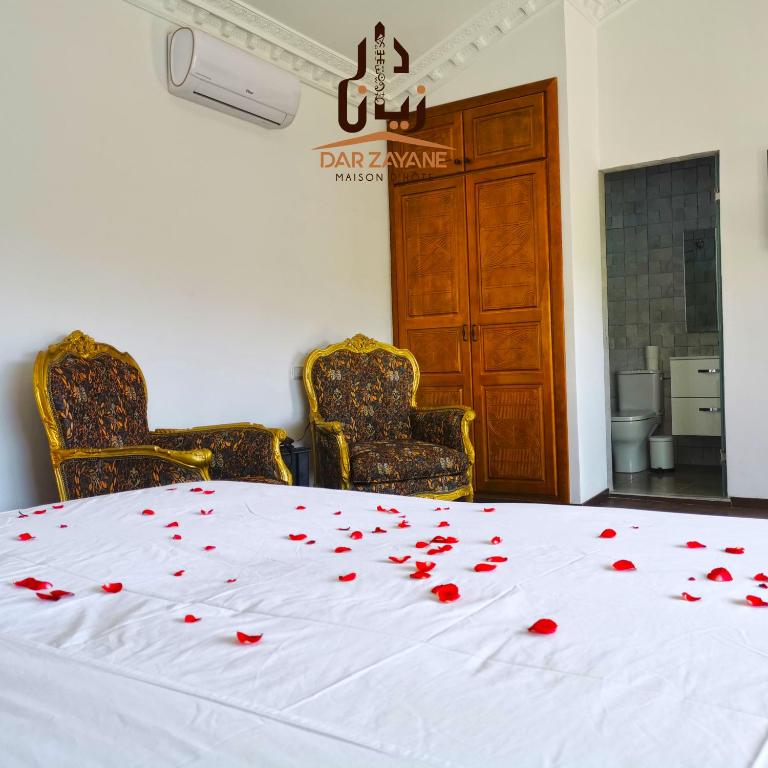a white bed with red rose petals on it at Dar Zayane in Khenifra