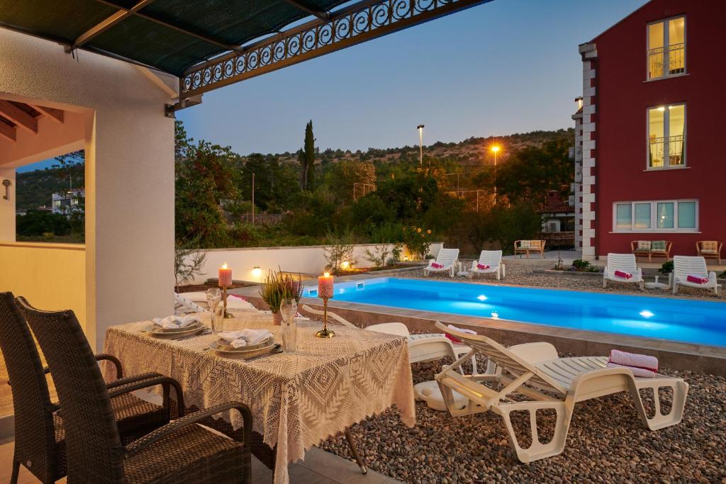 un patio con mesa, sillas y piscina en Villa Liberty en Cavtat