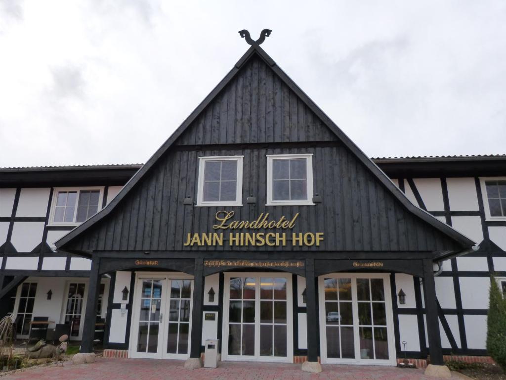 un edificio blanco y negro con un letrero. en Landhotel Jann Hinsch Hof en Winsen Aller