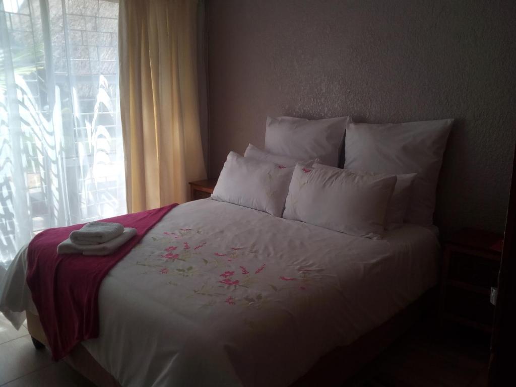 - une chambre avec un lit doté de draps blancs et une fenêtre dans l'établissement revival guest house, à Klerksdorp