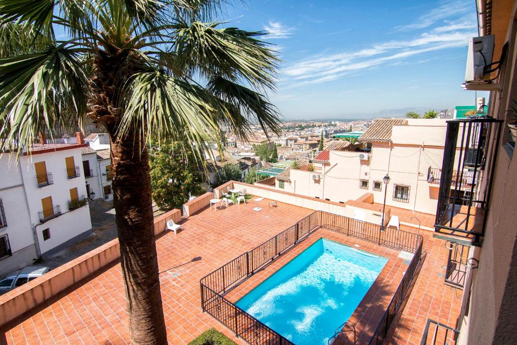 a view of a swimming pool from a building with a palm tree at Apartamento con unas maravillosas vistas a Granada in Granada