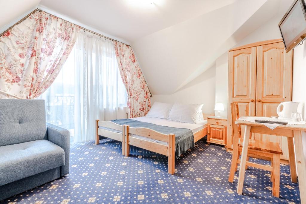 a bedroom with a bed and a chair and a window at Dunajecki Dworek in Biały Dunajec