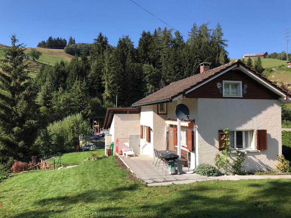 ein Haus auf einem Hügel mit einem grünen Hof in der Unterkunft Appenzellerland - Ferienhaus "Bömmeli" in Hundwil