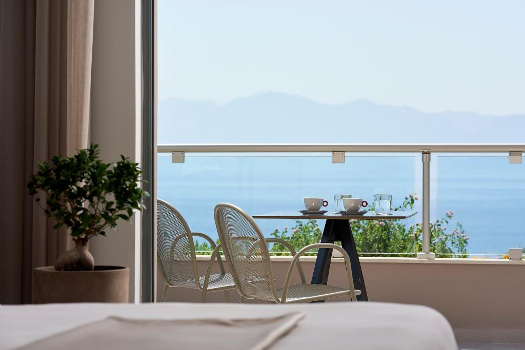 a room with a table and chairs in front of a window at Michelangelo Resort & Spa in Ágios Fokás