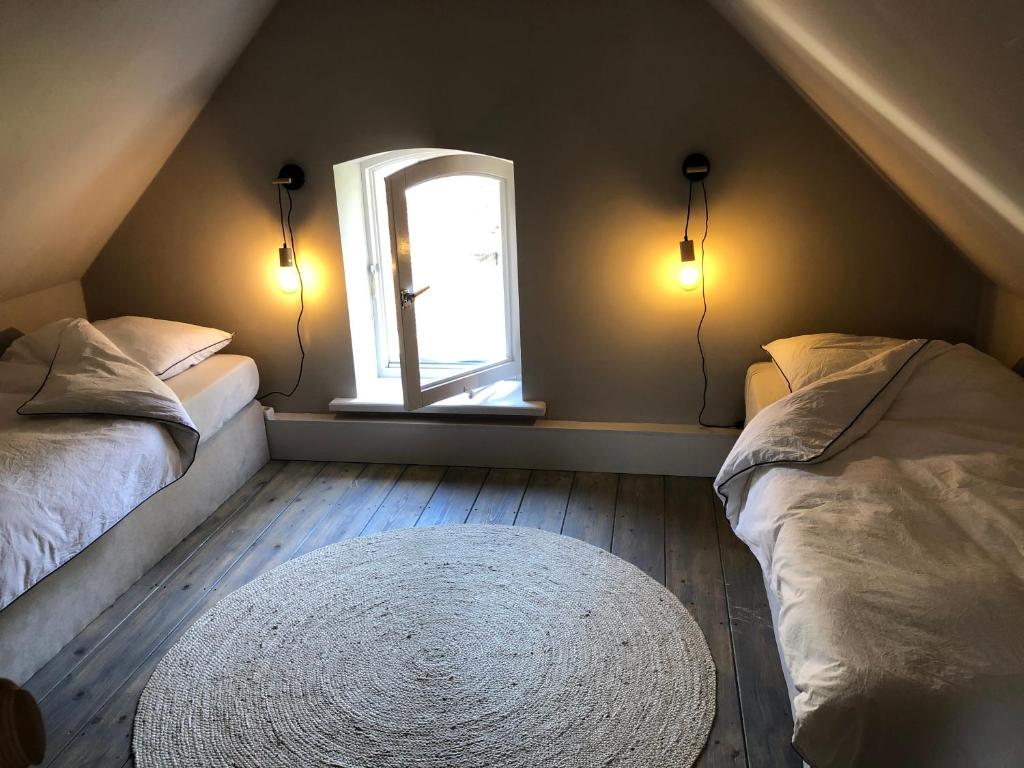 a attic bedroom with two beds and a window at Erve de Kippe. Vrij maar toch dichtbij. in Epse