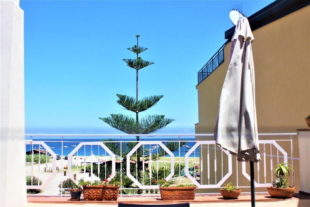 ein weißer Regenschirm auf dem Balkon eines Hotels in der Unterkunft Una Araucaria sul mare in San Giorgio