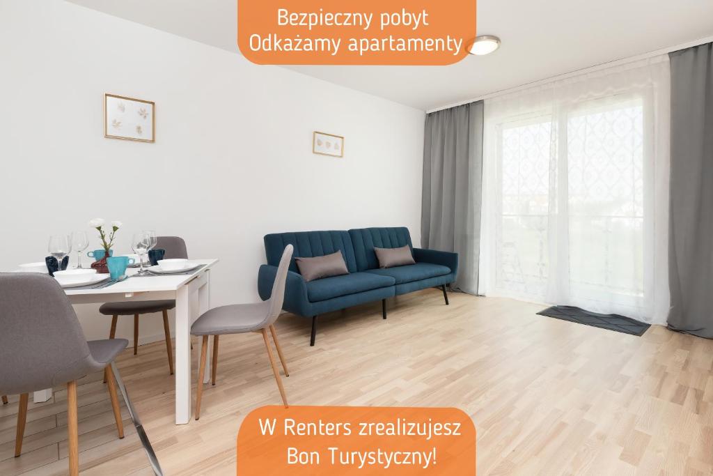 a living room with a blue couch and a table at Apartments Św. Brata Alberta by Renters in Gdańsk