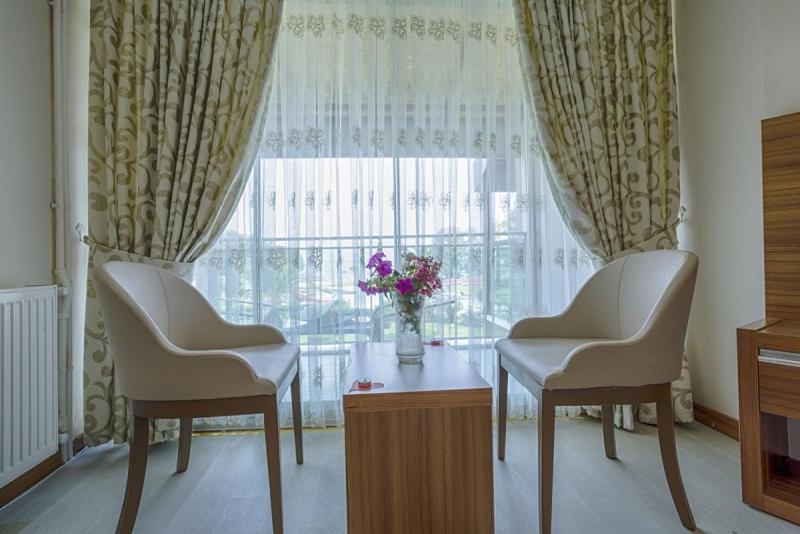Habitación con 2 sillas, mesa y ventana en RA Resort Otel, en Küçükkuyu
