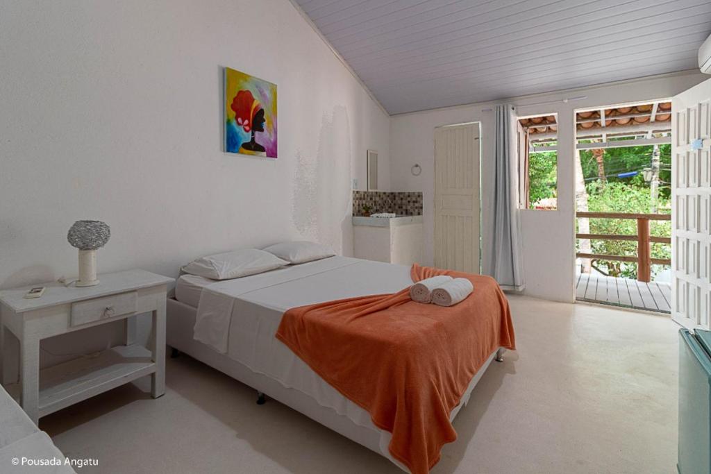 a bedroom with a bed with an orange blanket on it at Pousada Angatu Arraial - Rua do mucugê in Arraial d'Ajuda