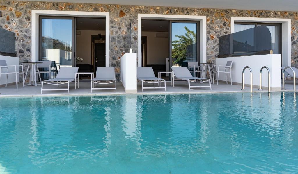
a swimming pool with two chairs and a television in front of it at Zoes Hotel & Suites in Faliraki
