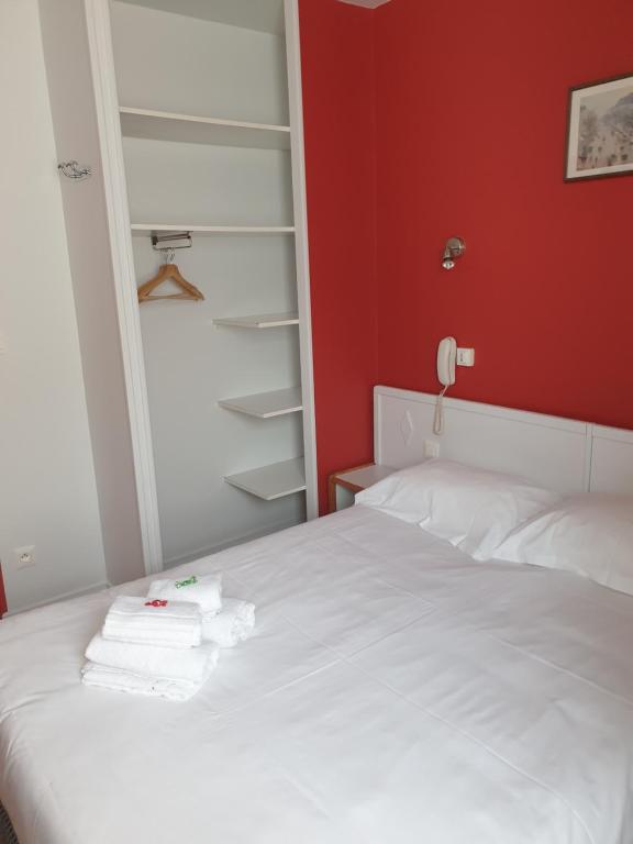 a bedroom with a white bed with a red wall at Hôtel Hermance in Bellegarde-sur-Valserine