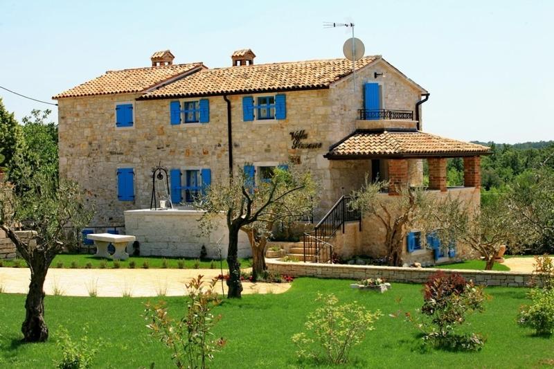 a large stone house with blue windows and a yard at Villa Simone in Žbandaj