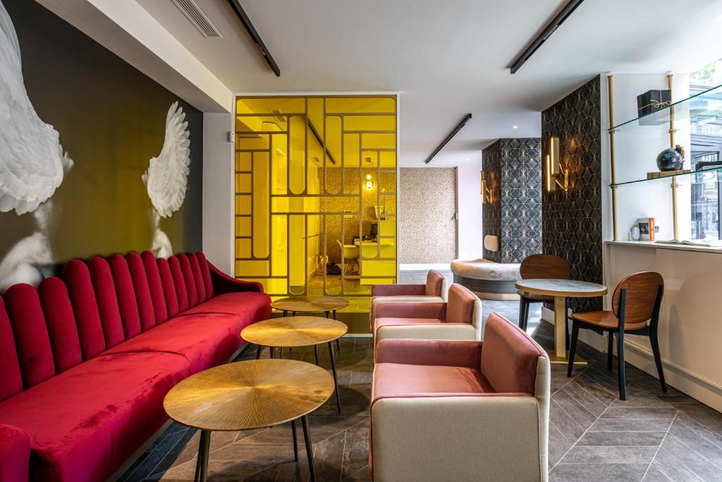 uma sala de estar com um sofá vermelho e mesas em Hôtel Nude Paris - Color Vision em Paris