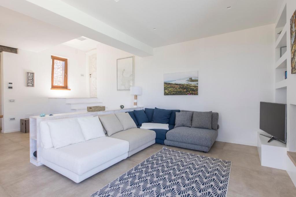un salon avec un canapé blanc et une télévision dans l'établissement Villa Tellus, à Stintino 13 autres photos