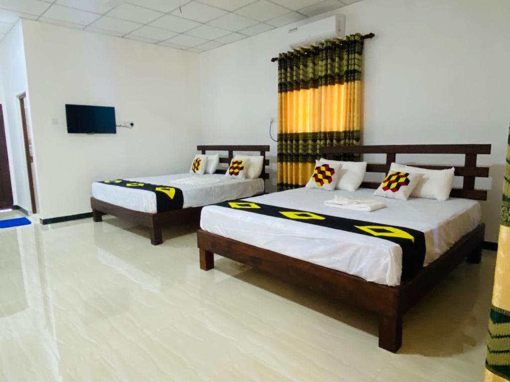 a bedroom with two beds and a flat screen tv at Hotel Surasa in Kurunegala