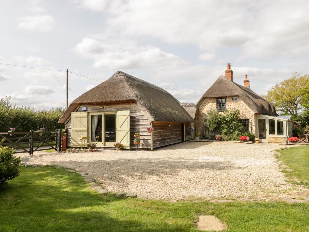 a thatch roofed house with a gravel driveway at The Barn at Rapps Cottage in Ilminster