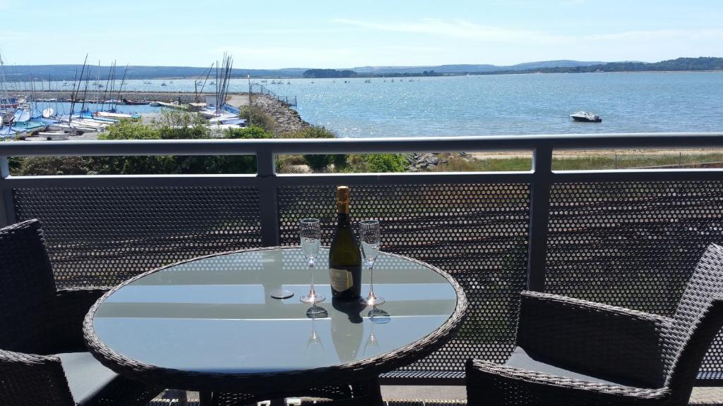 a glass table with a bottle of wine on a balcony at Beach Point in Poole