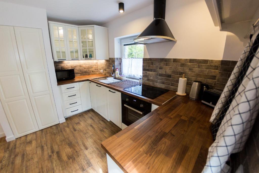 a kitchen with white cabinets and a wooden floor at Villa Lupus - apartament z prywatną sauną in Szklarska Poręba