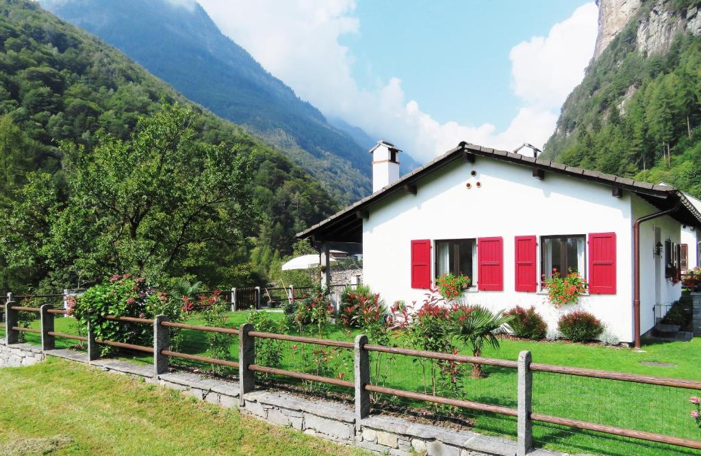 a white house with red shutters on a mountain at Casa Marco in Brione