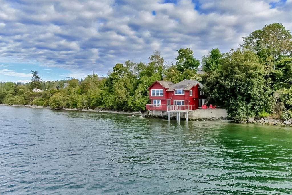 una casa roja en una isla en el agua en Heron House on the Cove, en Coupeville