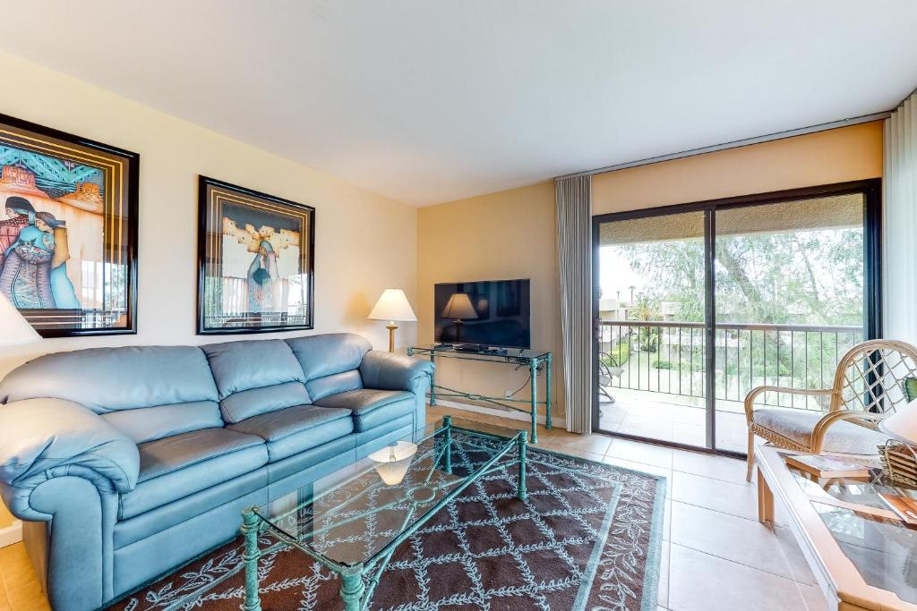een woonkamer met een blauwe bank en een tv bij Palm Desert Paradise Permit# STR2020-0085 in Palm Desert