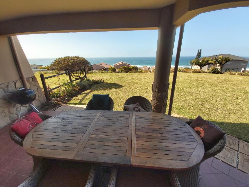 einen Holztisch auf einer Veranda mit Meerblick in der Unterkunft Kuta Beach Unit 7 in Margate