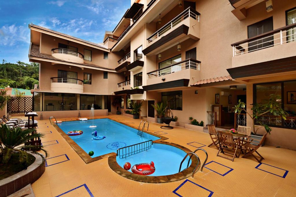 an apartment building with a large swimming pool at La Sunila Suites & Villas by WSI, Baga in Baga