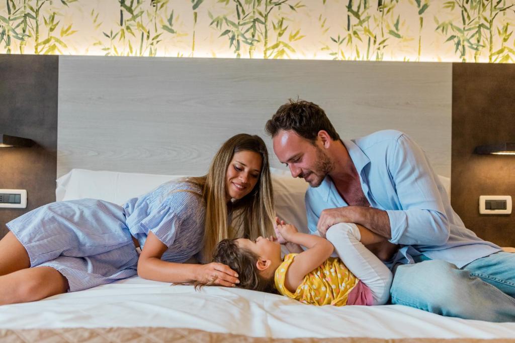 a family laying on a bed with a child at Hotel Prestige in Montesilvano