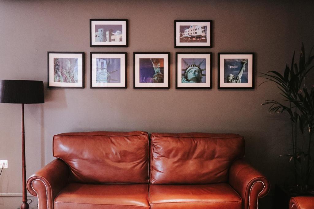 a brown leather couch in a living room with pictures on the wall at Le Monde Hotel in Edinburgh