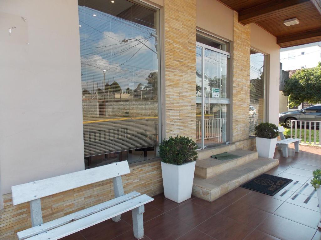 a building with two benches in front of a window at Hotel Visão in Ivoti