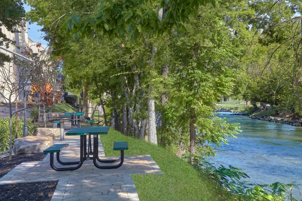 a picnic table and benches next to a river at The Inn On The River in Pigeon Forge
