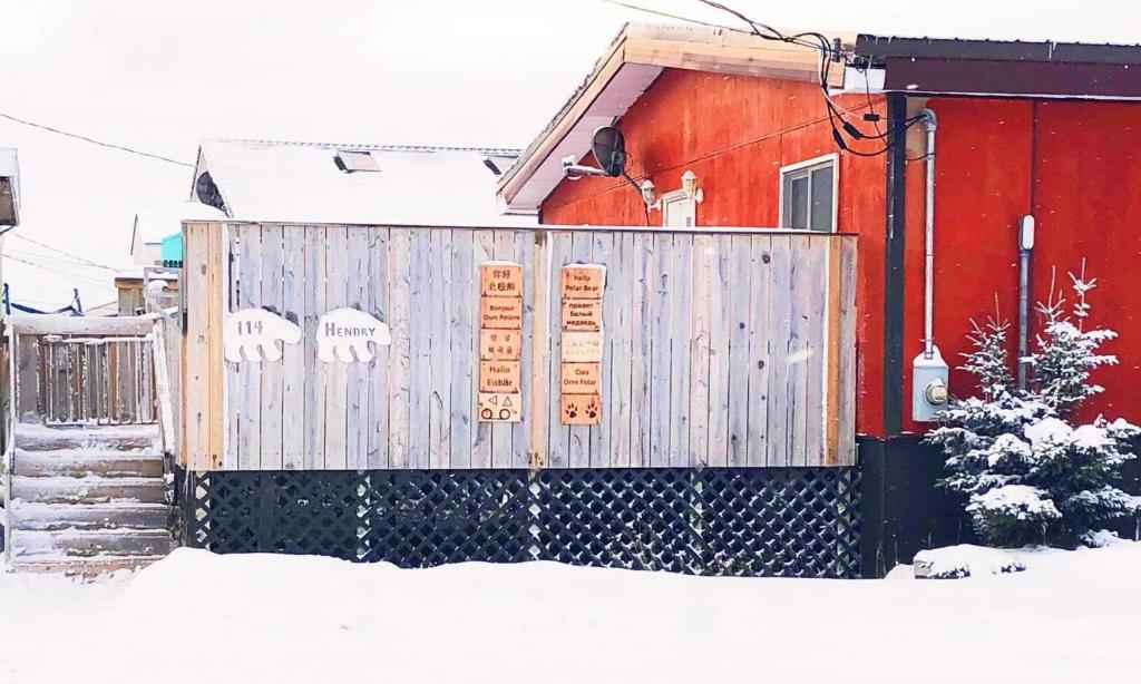 a fence in front of a red house in the snow at Sarah's dreamhouse B&B in Churchill
