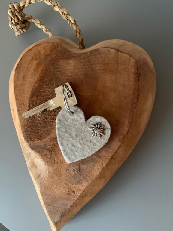 a wooden heart with a key on a necklace at Herzlappartment Allgäu in Wertach