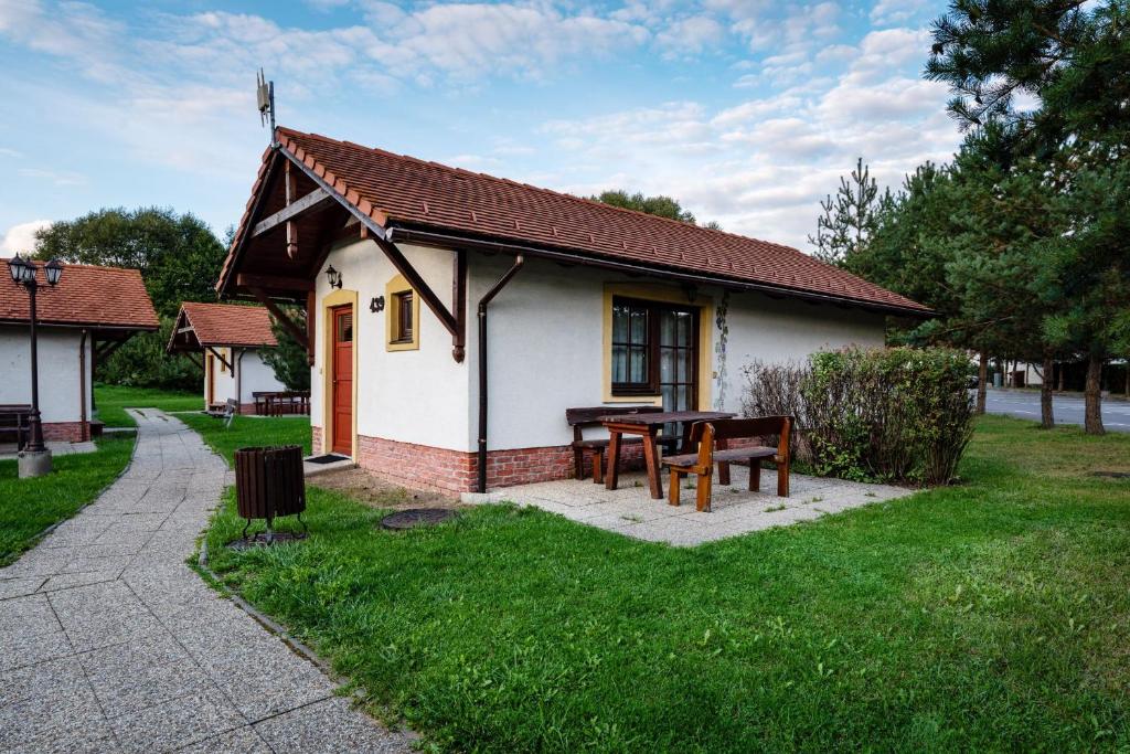een klein huis met een picknicktafel en een bank bij Chatka TATRALANDIA 439 in Liptovský Mikuláš
