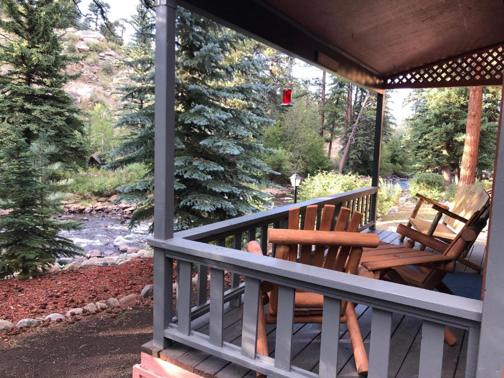 un porche con 2 bancos de madera y un río en Riverfront Mountain Cottage Retreat, en Estes Park