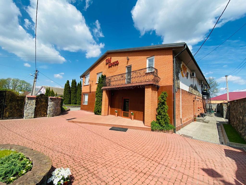 un edificio in mattoni con balcone su un vialetto di mattoni di SN Hotel a Sloboda Zasluchʼ