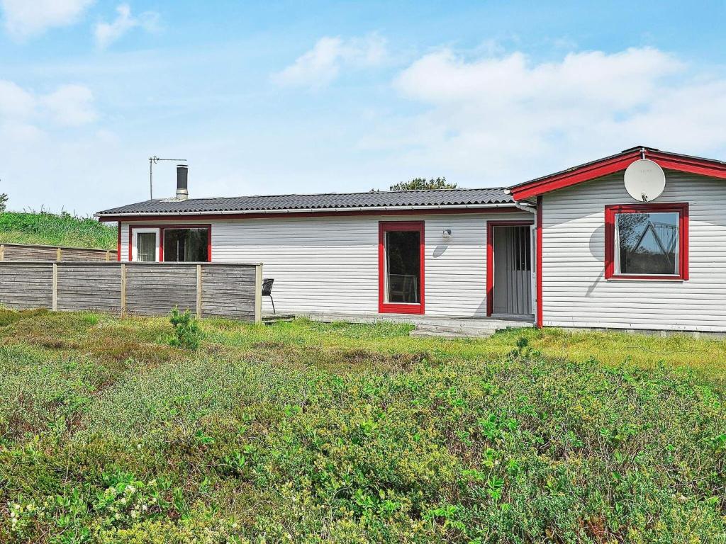 Casa blanca con ventana roja y valla en 4 person holiday home in Hvide Sande, en Bjerregård
